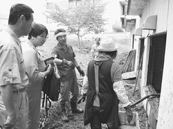 （写真）丸家旅館の泥のかき出し作業を見つめる高橋氏（左から２人目）ら＝16日、盛岡市